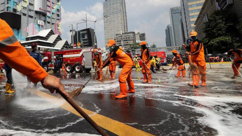 Varios operarios y bomberos limpian una avenida tras los disturbios | EFE/ Bagus Indahono