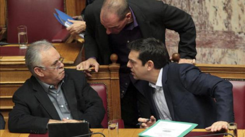 El primer ministro griego, Alexis Tsipras (d), conversa con su ministro de Finanzas, Yanis Varufakis (c), y su viceprimer ministro, Yanis Dragasakis.- EFE