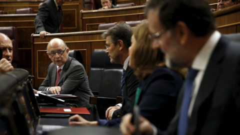 El ministro de Hacienda, Cristóbal Montoro, conversa, antes del comienzo de la sesión de control en el Pleno del Congreso, con el presidente del Gobierno, Mariano Rajoy, la vicepresidenta Soraya Saenz de Santamaria, y el titular de Justicia