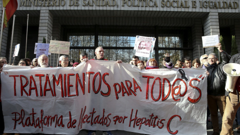 Varias personas participan en una cadena humana, organizada por la Plataforma de Afectados por la Hepatitis C, rodeando el Ministerio de Sanidad para exigir tratamientos para la enfermedad.- EFE/Ballesteros