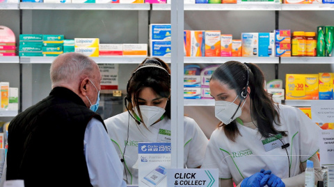 Dos empleadas de una farmacia atienden a un cliente.