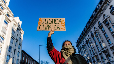 Una mujer sujeta una pancarta durante una manifestación del movimiento ‘Juventud por el Clima’, frente al Congreso de los Diputados, a 3 de marzo de 2023, en Madrid.