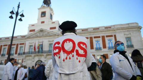 Un hombre con una bata donde se puede leer "SOS" en una concentración en defensa de la Atención Primaria, a 13 de noviembre de 2021, en Madrid