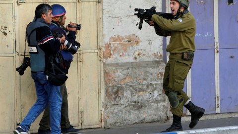 Un soldado israelí apunta con su arma a unos fotógrafos durante enfrentamientos con manifestantes palestinos en una protesta en la ciudad cisjordana de Hebrón. / REUTERS