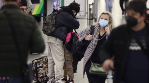 Dos personas, con maletas, se abrazan junto al control de equipajes, en el día en que arranca la operación salida de Semana Santa 2022, en la estación Madrid - Puerta de Atocha