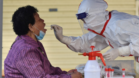 Un trabajador de la salud que usa un equipo de protección personal recolecta muestras de hisopos de un residente (18/4/21)