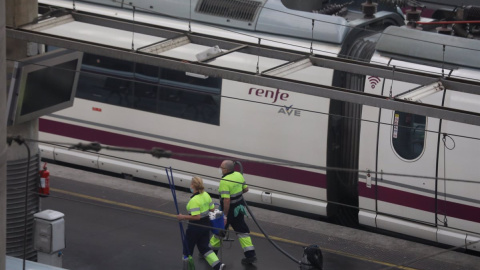 Dos trabajadores pasan junto a un tren AVE de Renfe en un andén en la estación de Atocha, en Madrid. E.P./Marta Fernández Jara