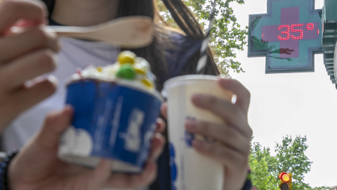 Unas personas se refrescan con helados en Zaragoza este jueves.