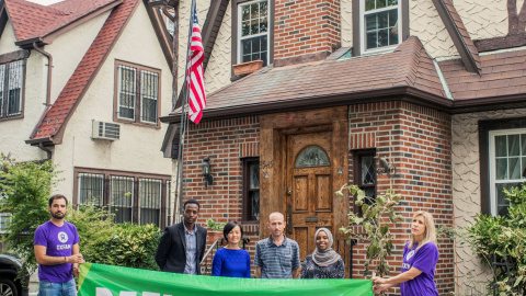 Integrantes de Oxfam sostienen una pancarta de apoyo a los refugiados frente a la casa de la infancia de Trump. / Reuters