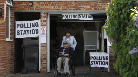 Dos personales salen de votar en una mesa electoral instalada en el garaje de una casa de Croydon. - AFP