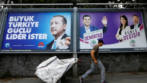 Un recolector de basura camina entre carteles electorales en Turquía. - REUTERS