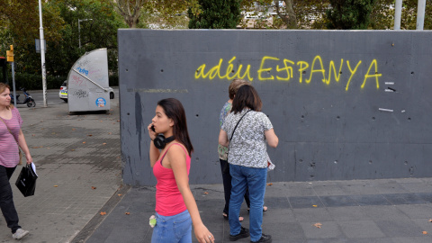 Varias personas pasan por delante de una pintada en Barcelona que, en catalán, dice 'Adiós, España'. REUTERS/Vincent West