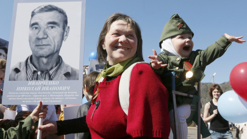 A woman with a child holds picture of World War Two soldier as she takes part in the Immortal Regiment march during the Victory Day celebrations in Divnogorsk. REUTERS/Ilya Naymushin