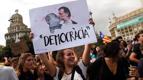 Una mujer sostiene un cartel que muestra al presidente de Gobierno, Mariano Rajoy, y al dictador Francisco Franco, sobre el mensaje "Democracia", durante la manifestación en repulsa de las escenas de violencia policial que se vivieron el 1-