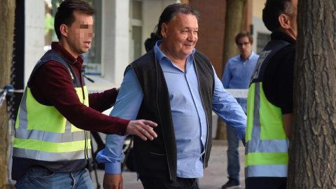 El presidente del Huesca, Agustín Lasaosa,d., junto a un policia a su salida de las oficinas del club tras ser detenido. /EFE