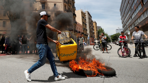 Un repartidor de Glovo quema una mochila durante una protesta tras la muerte de un compañero en Barcelona.-REUTERS/ALBERT GEA