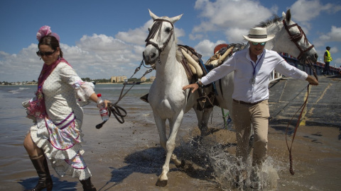 Los peregrinos cruzan el río Guadalquivir en ruta hacia el santuario de El Rocío en el parque nacional de Doñana durante la peregrinación anual de El Rocío.