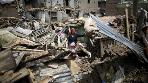 Una mujer permanece entre los escombros de uno de los edificios derruidos en la ciudad de Sankhu. - REUTERS