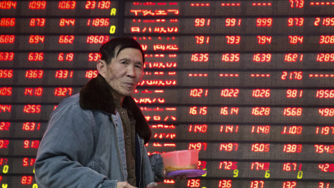 Un hombre pasa por delante del panel que muestra información de los mercados, en un firma de bolsa en la ciudad china de Nanjing. REUTERS/China Daily