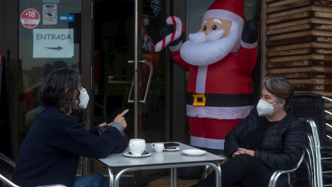 23/12/2020.- Dos personas conversan con la mascarilla puesta mientras se toman algo en la terraza de un bar en la víspera de Nochebuena, en Ourense.