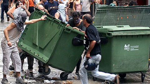 Un grupo de jóvenes cruza un contenedor en la calle durante los disturbios por el desalojo de un centro okupa en Pamplona en 1994.- EFE