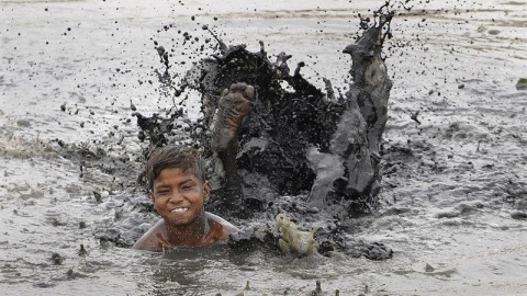 Un niño juega en una charca con agua contaminada durante un día caluroso en Nueva Delhi, India. EFE/Str