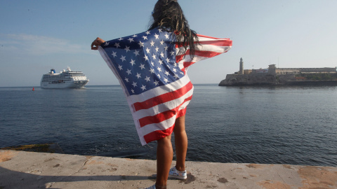 Una mujer con una bandera de Estados Unidos observa la llegada del primer crucero en navegar entre Estados Unidos y Cuba desde 1959. REUTERS