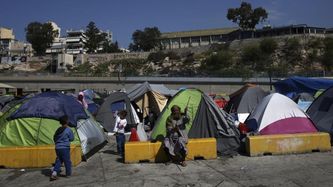 Una refugiada repara su tienda de campaña en el campamento improvisado en el puerto del Pireo, Atenas. - EFE