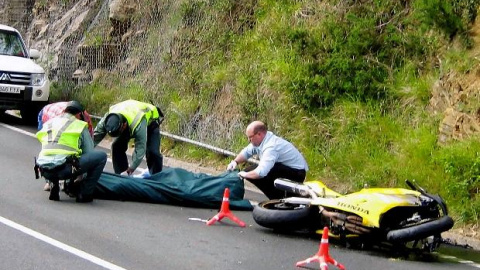 Miembros de la Guardia Civil de Tráfico y del servicio de emergencias se disponen al traslado de una de las tres víctimas mortales, tres motoristas, que fallecieron hoy en el accidente de tráfico registrado en el kilómetro 16 de la carreter