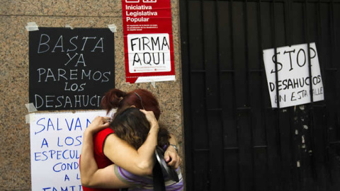 Dos mujeres se abrazan en la puerta de la casa de la que acaban de ser desahuciadas en Madrid, en 2012.- REUTERS/SUSANA VERA (ARCHIVO)