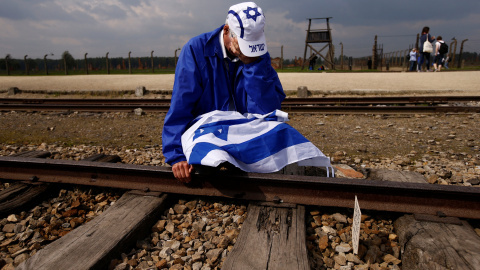 Un hombre sentado junto a las vías del tren del campo de concentración nazi de Auschwitz-Birkenau. REUTERS/Kacper Pempel