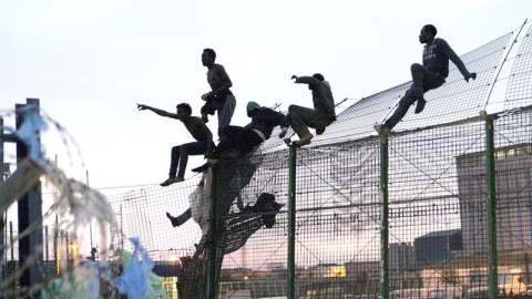 Un grupo de personas intentan saltar la frontera de Melilla. EFE