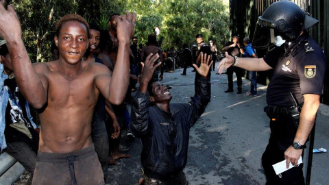 Los migrantes frente al cuerpo de la Policía Nacional/EFE