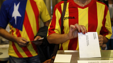 Una ciudadana deposita su voto en una mesa de en un colegio electoral de Barcelona, en las elecciones del 27-S. EFE/ Quique García