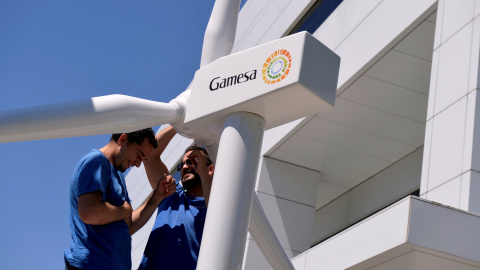 Dos operarios con la maqueta de un aerogenerador en la entrada de la sede de Gamesa, en Zamudio. REUTERS