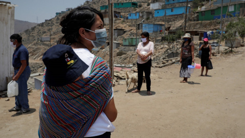 Unas personas esperan con ollas para recibir alimentos en el asentamiento humano de Buena Vista el 2 de febrero de 2021, en el populoso distrito limeño de Villa María del Triunfo, en Lima (Perú).