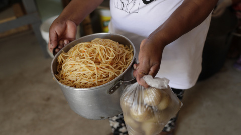 Una persona carga una olla con alimento en el asentamiento humano de Buena Vista el 2 de febrero de 2021, en el populoso distrito limeño de Villa María del Triunfo, en Lima (Perú).