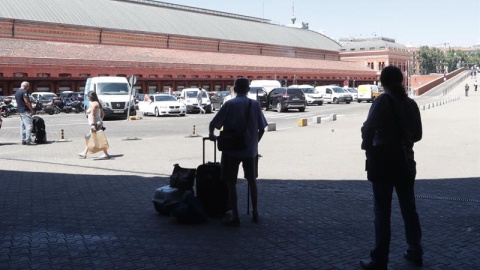 Pasajeros esperan en la estación de Atcocha en madrid, sus compañeros taxistas en huelga se concentran frente a la parada de la estación de Atocha en Madrid.-EFE/Zipi