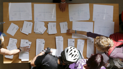 Varias personas escogen su papeleta para las elecciones al Parlamente de este 27-S en una mesa de un colegio electoral de Barcelona. REUTERS/Albert Gea