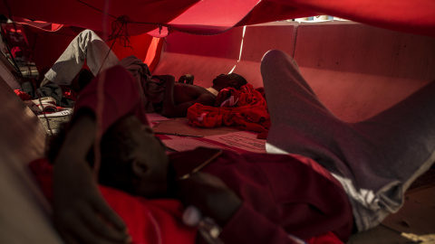 Dos migrantes se protegen del sol bajo una manta en el puerto del Algeciras. Han pasado varias noches allí debido al colapso en los polideportivos y dependencias policiales tras llegar en patera a España. JAIRO VARGAS