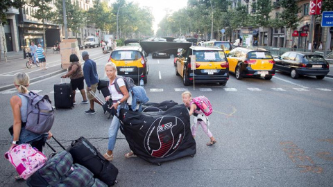 31/07/2018.- Unos turistas llevan sus maletas mientras los taxistas mantienen las concentraciones en el centro de la ciudad con motivo de la huelga iniciada el pasado 25 de julio, por el conflicto de las licencias VTC (alquiler de vehículos