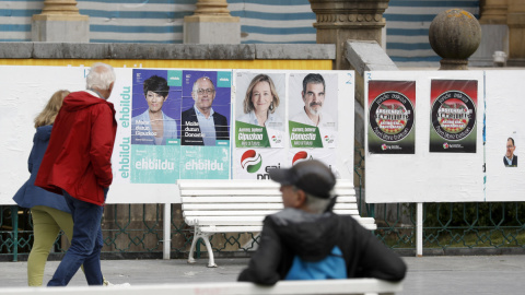 Unos ciudadanos observan varios carteles electorales este martes en San Sebastián, a 16 de mayo de 2023.