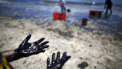 Varios voluntarios limpian una de las playas afectadas por el vertido. / LUCY NICHOLSON (REUTERS)