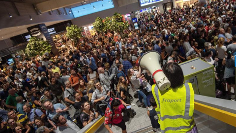 Personal del aeropuerto informa a pasajeros y visitantes mientras esperan a que se termine la evacuación en el aeropuerto de Fráncfort (Alemania), hoy, 7 de agosto de 2018. La evacuación preventiva de una parte de la Terminal 1 del aeropuer