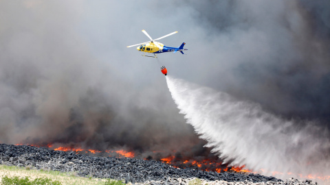 Un helicóptero trata de sofocar las llamas del incendio de neumáticos en Seseña.- REUTERS/Sergio Perez