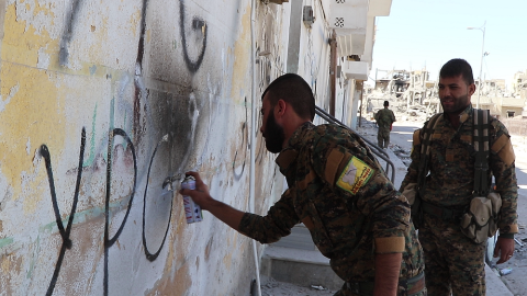 Combatientes de la milicia kurda YPG realizan una pintada en las calles de Raqqa./ FERRAN BARBER