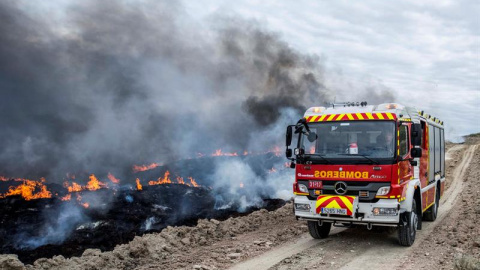 Un camión del cuerpo de bomberos pasa junto a los neumáticos que arden en Seseña, Toledo. EFE/Ismael Herrero