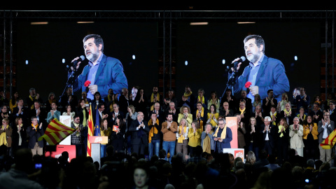 La imagen del presidente de ANC y número dos de la lista de Junts per Catalunya aparece en sendas pantallas mientras por megafonía suena una grabación de su voz, en un mitin de la candidatura soberanista en Barcelona. REUTERS/Albert Gea