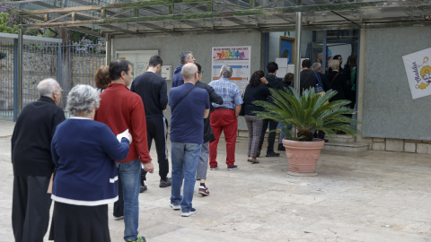 Un grupo de personas esperan a las puertas de un colegio electoral en la Comunitat Valenciana