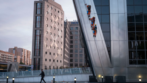 Un policía camina debajo de los activistas de Greenpeace al inicio de la escalada. GREENPEACE.